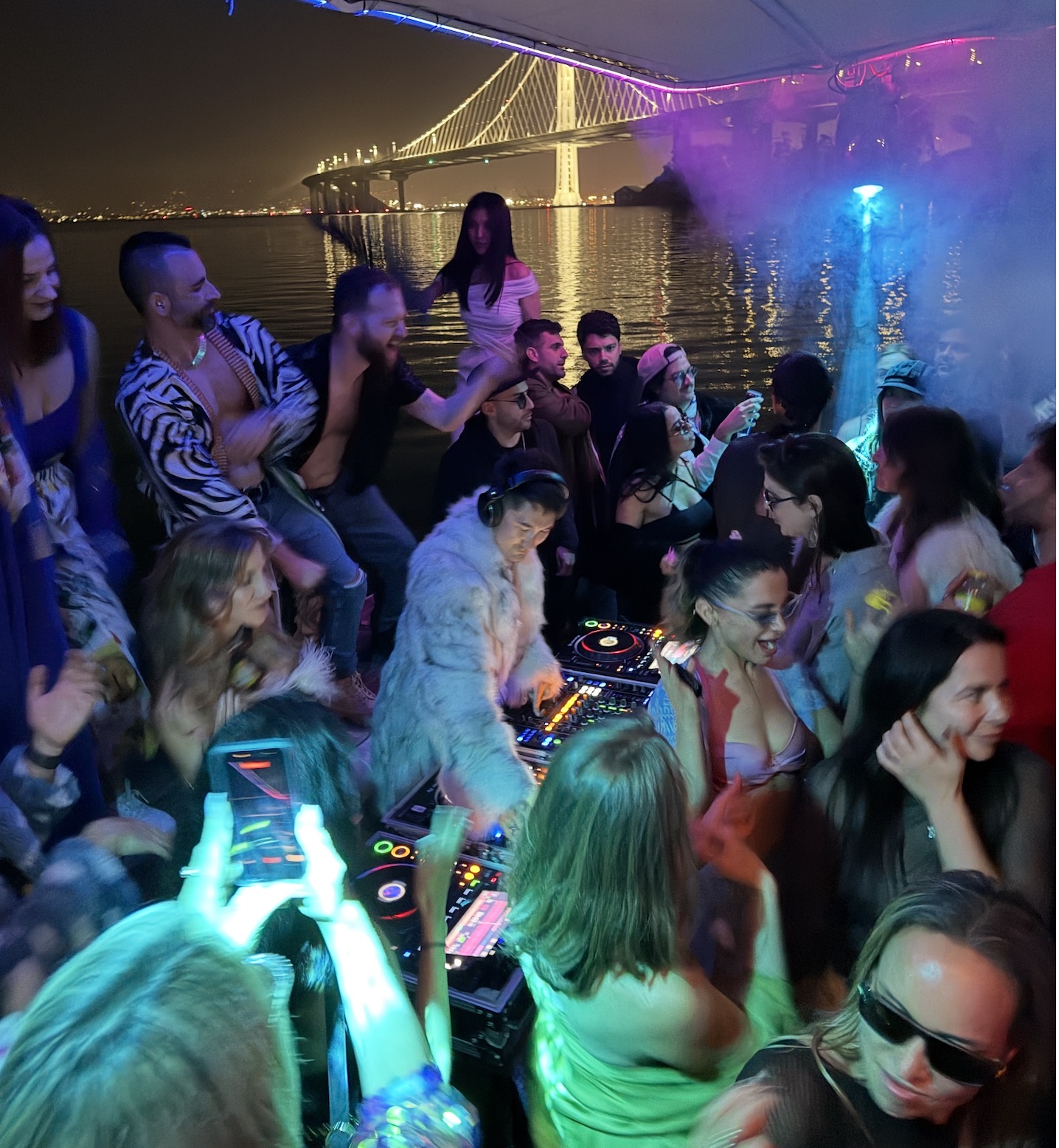 Friends dancing aboard First Sight with the Bay Bridge lit up behind them